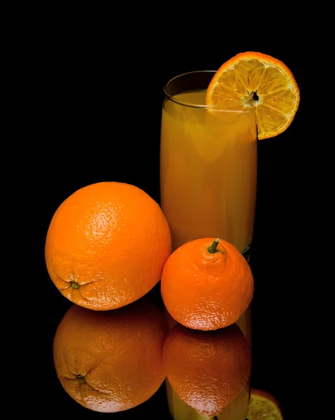 Mandarina, naranja y vaso de jugo sobre fondo negro — Foto de Stock