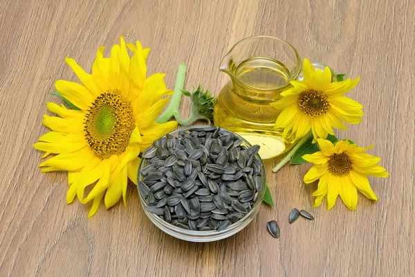 Sunflower seeds and flowers, sunflower oil on board — Stock Photo, Image