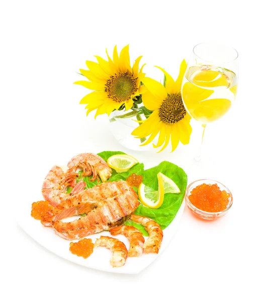 Fried fish, shrimp and caviar, a glass of wine and sunflowers on — Stock Photo, Image