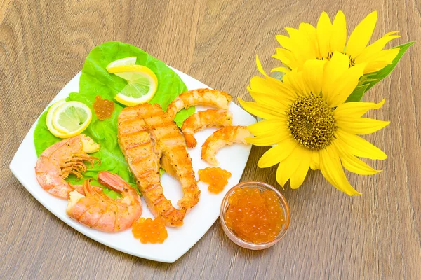 A piece of fried fish, shrimp, caviar and a bouquet of sunflower — Stock Photo, Image