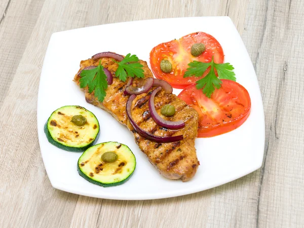 Pedaço de carne assada com legumes em um prato branco — Fotografia de Stock