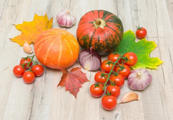 Vegetables and autumn leaves on a wooden board — Stock Photo, Image