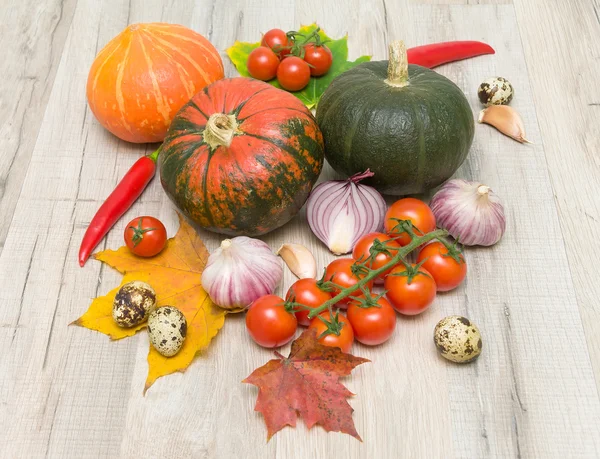 Ripe vegetables and autumn maple leaves on a wooden board — Stock Photo, Image