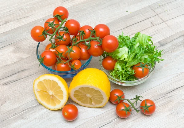 Pomodorini maturi, fregio di limone e insalata — Foto Stock