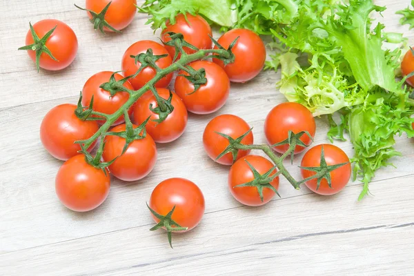 Tomates cereja maduros e friso de salada em uma mesa de madeira — Fotografia de Stock