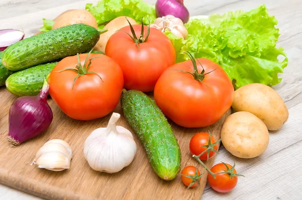 Färska grönsaker på en skärbräda på ett träbord närbild — Stockfoto