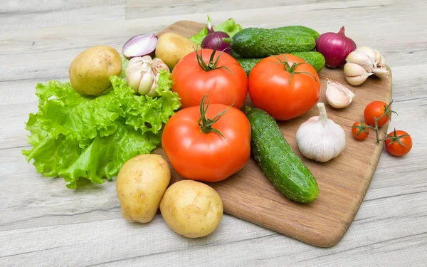 Groenten op een snijplank op een houten tafel — Stockfoto