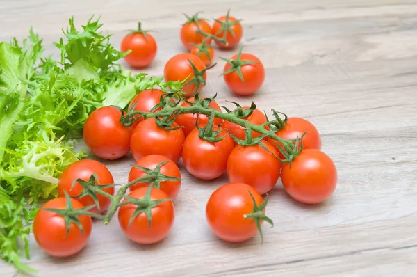 Wiśniowe pomidory i sałata fryz zbliżenie na drewnianym stołem — Zdjęcie stockowe