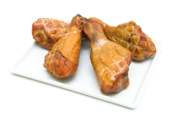Gebratene Hühnerkeulen auf einem Teller auf weißem Hintergrund — Stockfoto