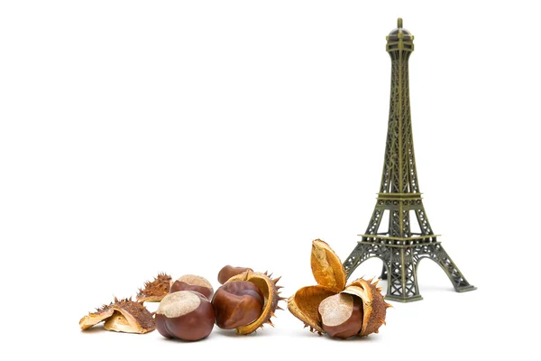 Mature chestnuts and the figure of the Eiffel Tower on a white b — Stock Photo, Image