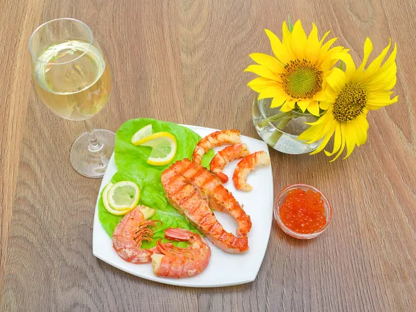 Grillad fisk med citron, röd kaviar och räkor, ett glas vin — Stockfoto