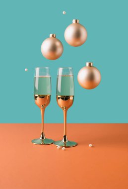 Üzerinde kutlama süsleri asılı iki altın şampanya kadehi. Gerçeküstü Yeni Yıl Minimum Konsepti