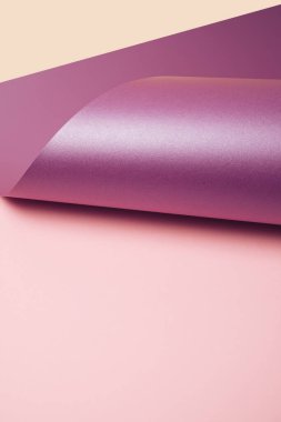 Mor metalik kağıt, pastel pembe ve sarı arka planda yuvarlanmış. Asgari soyut arkaplan