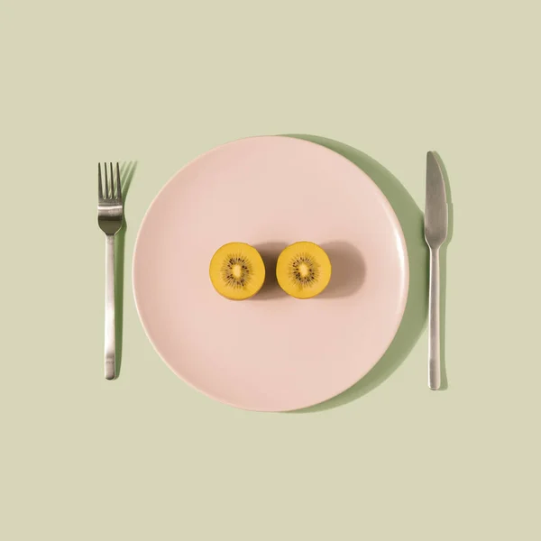 Dua Kiwi Kuning Setengah Pada Piring Merah Muda Pastel Konsep — Stok Foto