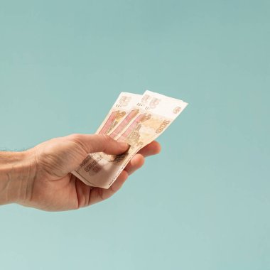 Pastel mavi arka planda Rus rublesi banknotları tutuyor. Rus ekonomisinin kavramsal geçmişi.