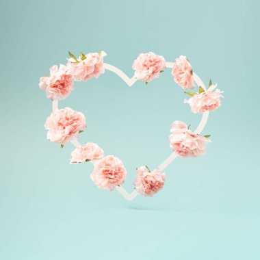 Flowers arranged in a heart shape on a pastel blue background. Romance and love minimal studio shot.
