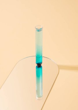 Sarı arka plandaki aynanın üzerinde duran tek bir test tüpü. Alternatif tıp konsepti.