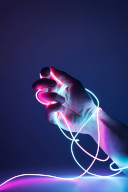 Karanlık bir arka planda neon kabloyla bağlanmış bir el. Sanal yaşam konsepti.