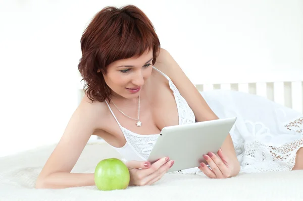 Γυναίκα με ένα πράσινο μήλο και το δισκίο κρεβάτι ανάγνωση ebook — Φωτογραφία Αρχείου