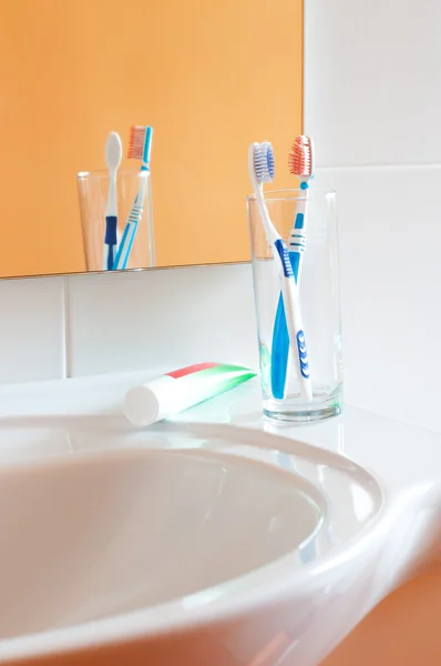 Cepillos de dientes coloridos en un vaso en el baño —  Fotos de Stock