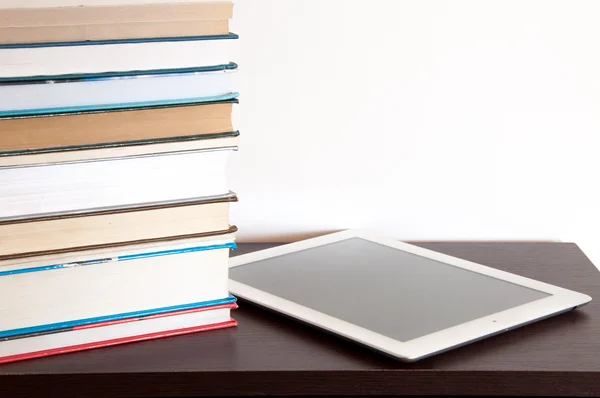 Lector de libros electrónicos y pila de libros sobre una mesa — Foto de Stock