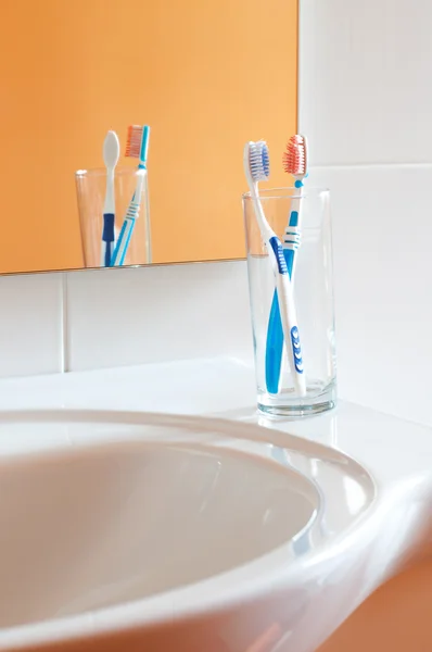 Kleurrijke tandenborstels in een glas in de badkamer Stockfoto