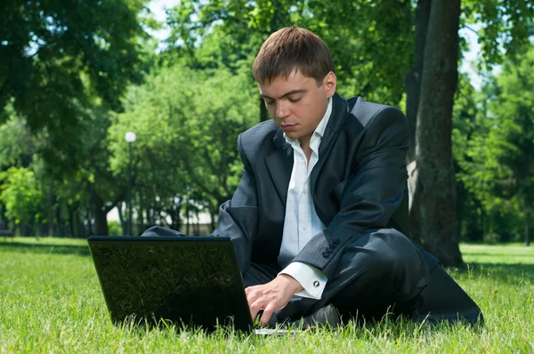 Homem de negócios dormindo no trabalho em um laptop na grama — Fotografia de Stock