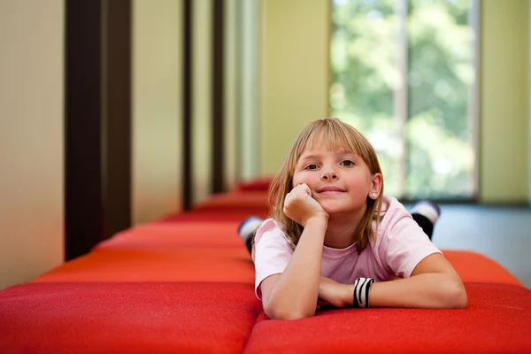 Petite fille sur un banc dans une pièce ensoleillée — Photo