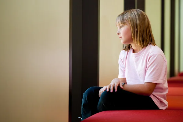 Kleines Mädchen auf einer Bank in einem sonnigen Raum — Stockfoto