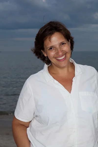 Mulher feliz em uma camisa branca na praia em um dia nublado — Fotografia de Stock