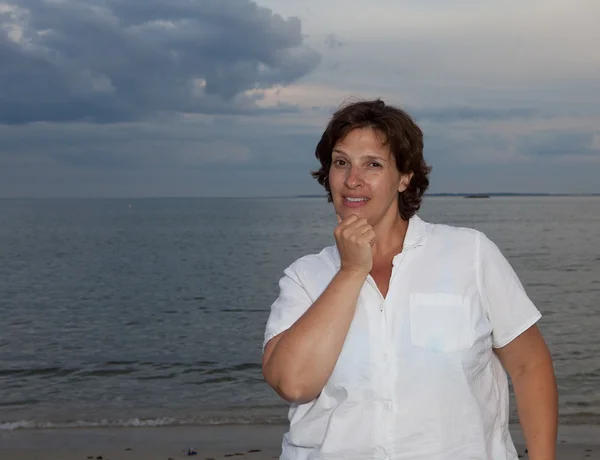 Happy woman in a white shirt on the beach on a cloudy day — Stock Photo, Image