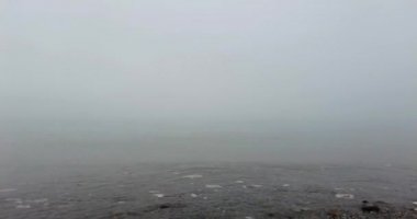 Sakin dalgalar sisli bir kış gününde kıyıya vurur.