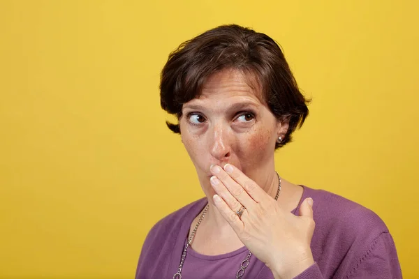 Atrakcyjna Dojrzała Kobieta Fioletowej Bluzce Żółtym Tle Dłonią Nad Ustami — Zdjęcie stockowe
