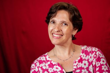 Kırmızı arka planda çekici olgun esmer kadın. Gülümseyen, mutlu yaşam tarzı konsepti.