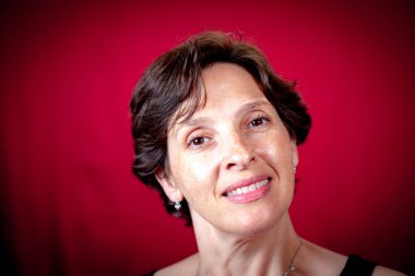 Kırmızı arka planda çekici olgun esmer kadın. Gülümseyen, mutlu yaşam tarzı konsepti.