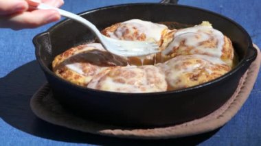 Cinnamon buns baked in cast iron outside. High-quality 4k footage shot outside on a sunny day