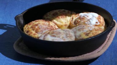Cinnamon buns baked in cast iron outside. High-quality 4k footage shot outside on a sunny day