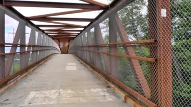 Slow pan of a pedestrian bridge over a highway on a partly cloudy day in the summer.