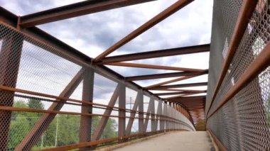 Slow pan of a pedestrian bridge over a highway on a partly cloudy day in the summer.