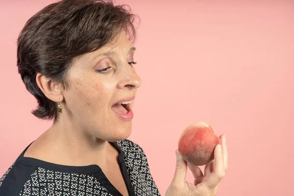 Brunette Woman Her 50S Studio Pink Background Eat Peach — Stok fotoğraf