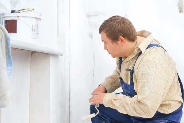 Constructor mirando a la pared de pintura con rodillo en las manos — Foto de Stock