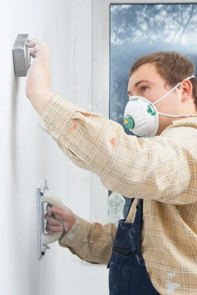 Joven constructor puliendo la pared — Foto de Stock