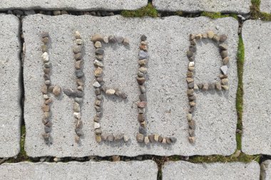 Gri kaldırımdaki yazıya yardım et. Yazı, çakıl taşlarından yapılmış. Yüksek kalite fotoğraf
