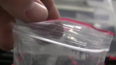 Civatalar düzenleyiciye dökülür. Cıvata dükkanı. Organizatör kırmızı ve siyah. Cıvatalar sınıflandırılıyor