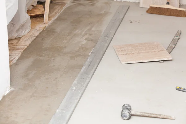 Workman's tools on a floor that is being tiled — Stock Photo, Image