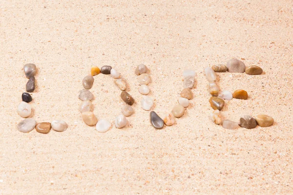 ビーチの砂の小石で書かれた単語の愛 — ストック写真