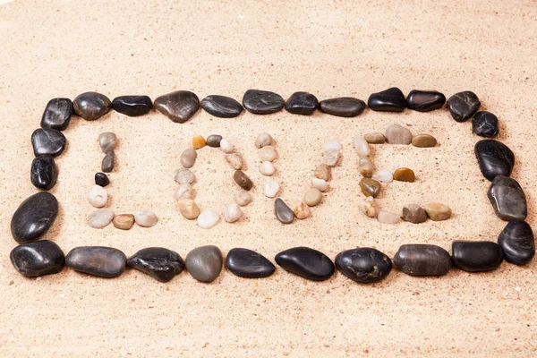 Parola amore scritto con ciottoli sulla sabbia di una spiaggia — Foto Stock