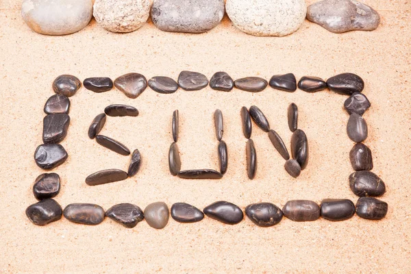Word sun written with pebbles on the sand of a beach — Stock Photo, Image