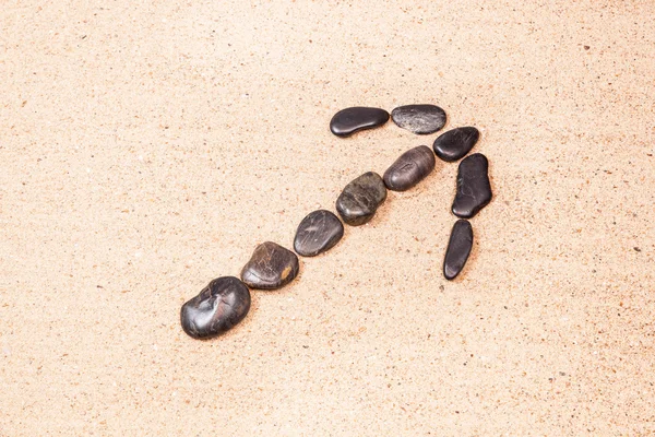 Pilen dras med stenar på stranden sand — Stockfoto