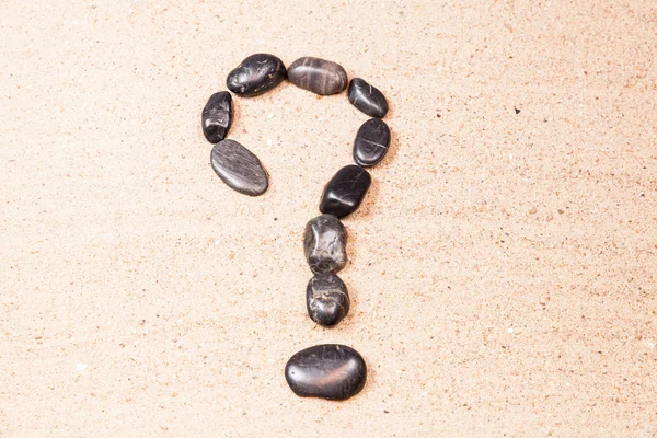 Frågetecken som dras med småsten på sanden på en strand — Stockfoto